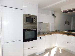 大塔拉哈尔PERLA Penthouse的厨房配有白色橱柜和微波炉
