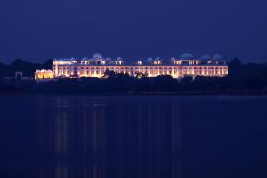 乌代浦乌代布尔宫殿丽笙度假村酒店的一座大型建筑在湖边晚上点燃