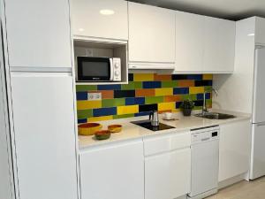 福恩吉罗拉Bnbook Medea Apartments 2的厨房配有白色橱柜和色彩缤纷的瓷砖墙