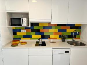 福恩吉罗拉Bnbook Medea Apartments 2的厨房配有白色橱柜和色彩缤纷的瓷砖墙