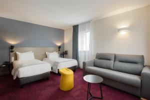 蒙托邦Sure Hotel by Best Western Les Portes de Montauban的酒店客房,设有两张床和一张沙发