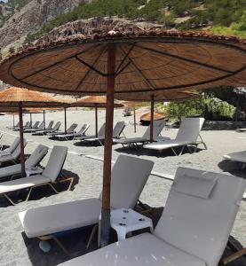 阿吉亚努美利Agia Roumeli Hotel的海滩上的一组椅子和一把遮阳伞