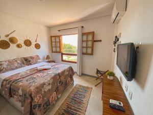 佩德拉斯港Maruê Guesthouse Porto de Pedras的一间卧室配有一张床和一台平面电视