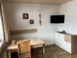 格伦Ferienwohnung Erika Masuck的一间设有桌子的用餐室和墙上的电视