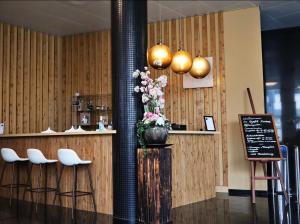 苏尔塞Wellness Hotel Aquafit Sursee的餐厅设有酒吧,酒吧内摆放着白色的凳子和鲜花
