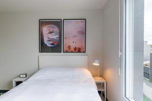 勒阿弗尔Student Factory Le Havre Les Docks的卧室配有白色的床,墙上有三幅画作