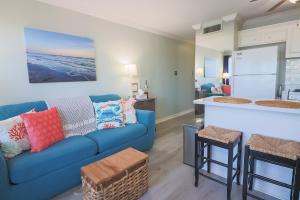 加尔维斯敦Charming Beachside Condo Lovely Pool Hot Tubs and Boardwalk的一间带蓝色沙发的客厅和一间厨房