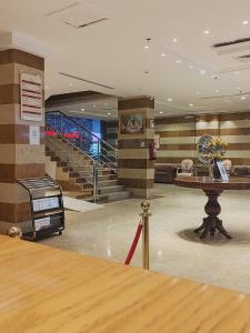 吉赞فندق تـاج النخبة - Taj Nakhba Hotel的大楼内带桌子和楼梯的大堂