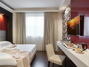格拉索比奥贝加莫机场冬季花园酒店的酒店客房设有一张床、一张书桌和一台电视机。