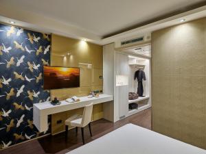 格拉索比奥贝加莫机场冬季花园酒店的更衣室设有书桌和墙上的电视