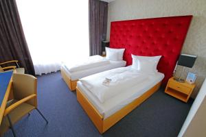Lichtenwalderugs Hotel am Schlosspark Lichtenwalde的配有红色床头板的酒店客房内的两张床