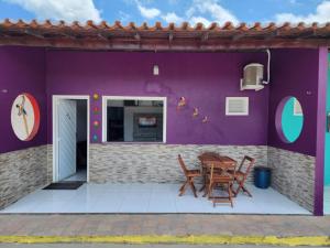 巴雷里尼亚斯BARREIRINHAS CHALÉ 12 PORTO DOS LENÇÓIS的紫色墙壁和桌椅的房子