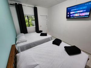 马利西亚斯Cantinho residencial的配有平面电视的客房内的两张床