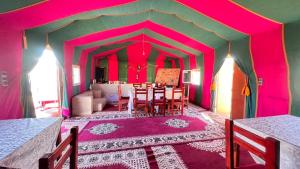 扎古拉Sahara Luxury Camp的用餐室设有粉红色的墙壁和桌椅