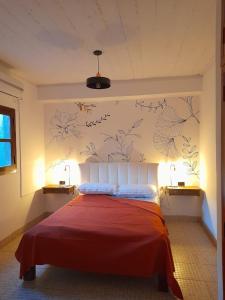 贝伦Alojamiento Belen Catamarca的卧室配有一张铺有红色床单的床,墙上挂着鲜花。