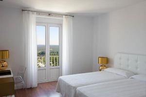 圣洛伦索-德埃斯科里亚尔埃克维多利亚酒店的白色的卧室设有床和大窗户