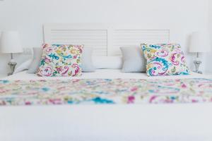 锡内乌Can Serrete的白色的床、色彩缤纷的枕头和白色床头板