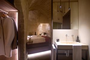 马泰拉Le Malve Cave Retreat的一间带水槽的浴室和一张位于客房内的床