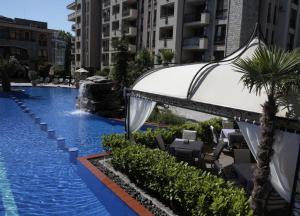 阳光海滩Cascadas Family Resort 2-Rooms Apartment sunny beach的一座带椅子和棕榈树的游泳池