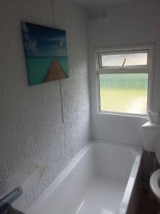 BursledonRockets's Retreat的带浴缸的白色浴室和窗户。