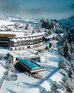 希洛谢克Travel Charme Ifen Hotel Kleinwalsertal的雪地中带游泳池的度假村