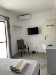 普拉亚Cantinho C - Alojamento Complementar的一间卧室配有一张床、一台电视和一把椅子