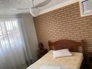 帕里普埃拉condomínio Porto di Mare Casa 22 ALAGOAS的一间卧室设有一张床和砖墙
