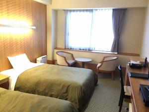 宫岛宫岛珊瑚酒店的酒店客房设有两张床、一张书桌和一个窗户。