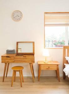 西归浦市Bandi House的一张带镜子、凳子和时钟的桌子
