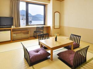 宫岛宫岛珊瑚酒店的客厅配有桌椅和电视。