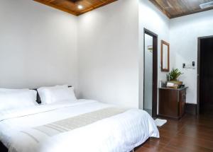 琅勃拉邦Villa Wanika的卧室设有白色的床和木制天花板。