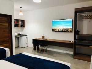 圣米格尔-杜斯米拉格里斯Marinho Suítes Milagres的一间卧室配有一张桌子和一台墙上的电视。