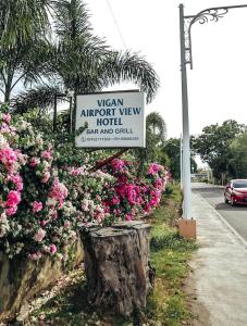 美岸Airport View Hotel Vigan的机场景酒店旁粉红色花的标志