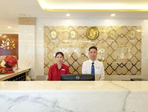 胡志明市Đông Kinh Hotel的站在电脑前的男人和女人