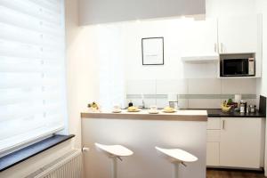 杜伊斯堡SECRET HIDEAWAYS cozySTUDIO 1 superior Apartment mit WiFi l 450m bis Uni l Zoo的厨房配有白色橱柜和白色凳子