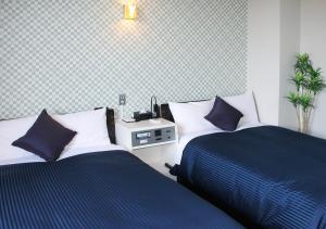 UchinadaHotel Livemax BUDGET Kanazawa-Idaimae的一间卧室配有两张带蓝白色枕头的床