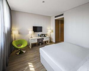 罗镇米兰国际会展中心NH酒店的一间卧室配有一张床、一张桌子和一把绿色椅子