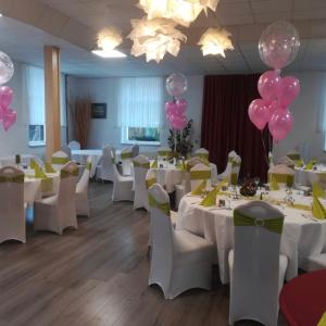 乌埃克尔明德利普加尔滕林登霍夫餐厅旅馆的宴会厅配有白色桌子和粉红色气球