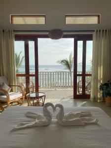 阿杭格默Lihinya Beach Villa Ahangama的两个天鹅在海边的床上心跳