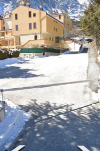 罗卡迪坎比奥Appartamento Residence Monte D'Ocre的一条有雪覆盖的街道,有建筑背景