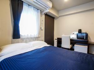 大阪HOTEL LiVEMAX Umeda Doyama的一间卧室设有蓝色的床和窗户。