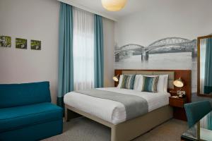 伦敦Seraphine Hammersmith Hotel的一间卧室配有一张床和一张蓝色椅子