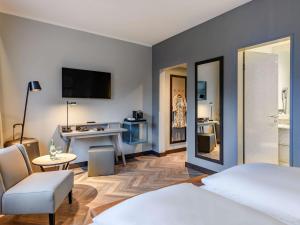 多特蒙德Mercure Hotel Dortmund Centrum的酒店客房,配有一张床、一张桌子和椅子