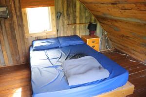 L’Anse-au-Griffon格里芬艳遇木屋旅舍的木制客房的一张床位,设有窗户