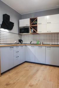 比得哥什Stara Drukarnia - Apartamenty typu Studio的厨房铺有木地板,配有白色橱柜。