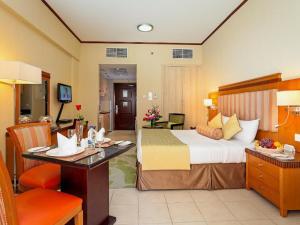 迪拜切尔西花园公寓酒店的酒店客房设有一张大床和一张书桌。