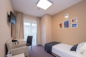 乌马格酒兹拉特娜瓦拉酒店的酒店客房配有一张床、一把椅子和一台电视。
