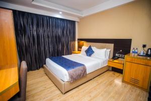 达卡Days Hotel Dhaka的配有一张床、一张书桌和一扇窗户的酒店客房