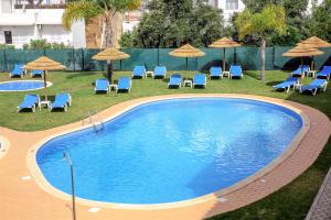 阿尔布费拉Aquamar Albufeira Aparthotel的一个带椅子和遮阳伞的大型游泳池