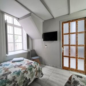 拉塞雷纳Casa Hostal Paso por La Serena的一间卧室设有一张床、一台电视和窗户。